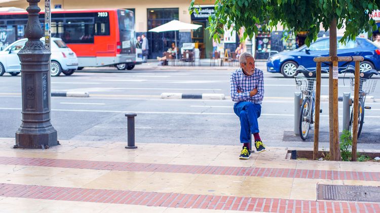Vagabond sitting on a cone watching streetlife
