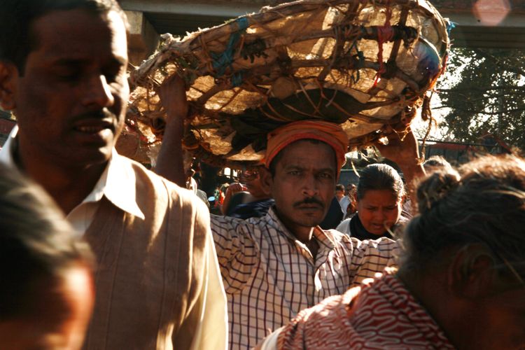 Man walking on the flower market with a basket on his head, looking intensively at the camera
